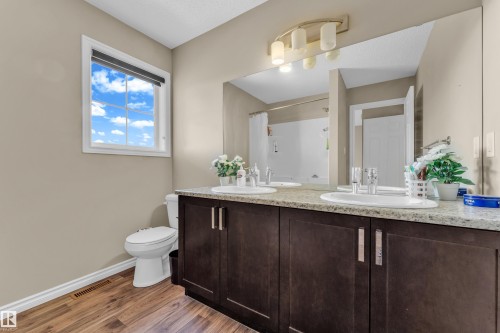 Bathroom featuring a dual vanity with a granite-style countertop, dark wood-finish cabinetry, and undermount sinks - 2526 19A Avenue, Edmonton, AB - Indoor Photo Showing Bathroom