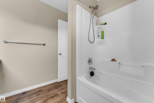 White acrylic tub and shower combination featuring a multi-function showerhead - 2526 19A Avenue, Edmonton, AB - Indoor Photo Showing Bathroom