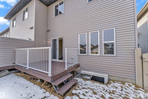 Rear exterior featuring a composite deck with white railings, a sliding glass door entry, and three large windows - 2526 19A Avenue, Edmonton, AB - Outdoor With Deck Patio Veranda With Exterior