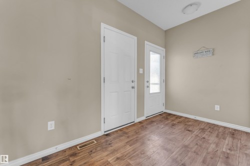 Entryway featuring wood-finish flooring, light tan walls, white baseboards, and two white doors with hardware - 2526 19A Avenue, Edmonton, AB - Indoor Photo Showing Other Room
