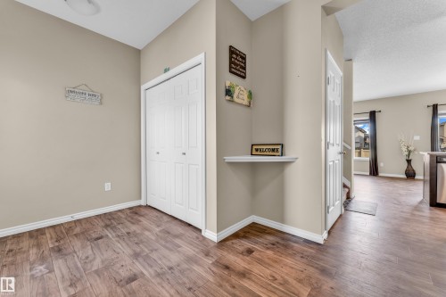 Spacious entryway featuring wood-finish flooring, neutral-toned walls, a double bifold closet, and a corner display shelf - 2526 19A Avenue, Edmonton, AB - Indoor Photo Showing Other Room