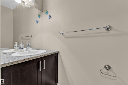 Bathroom vanity featuring a single basin sink, speckled countertop, and dark wood-finish cabinetry - 2526 19A Avenue, Edmonton, AB - Indoor Photo Showing Bathroom