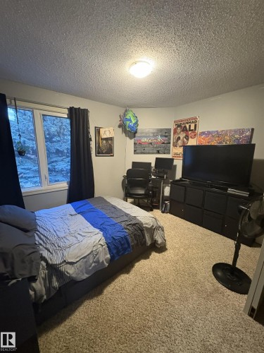 Carpeted room featuring a window with dark drapery, a ceiling-mounted light fixture, and textured ceiling - 79 Akinsdale Gardens, St. Albert, AB - Indoor Photo Showing Bedroom
