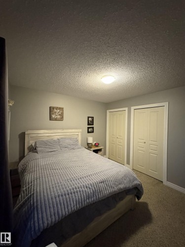 Bedroom featuring textured ceiling, flush mount lighting, two sets of bi-fold closet doors, wall-to-wall carpeting, and painted walls - 79 Akinsdale Gardens, St. Albert, AB - Indoor Photo Showing Bedroom