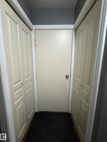 Hallway with a solid panel door, two bi-fold doors, and a dark carpeted floor - 79 Akinsdale Gardens, St. Albert, AB - Indoor Photo Showing Other Room