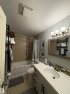 Bathroom featuring a white vanity with a rectangular undermount sink, a coordinating white countertop, and dark hardware - 