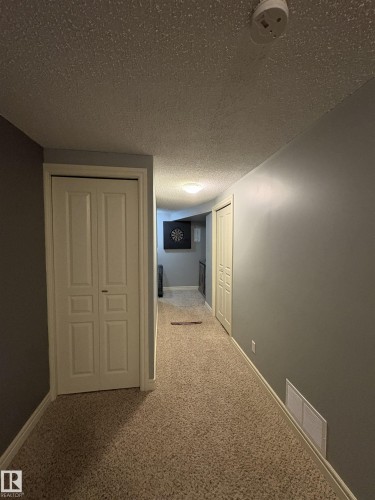 Carpeted hallway with two panel bi-fold doors, grey painted walls, and white trim - 79 Akinsdale Gardens, St. Albert, AB - Indoor Photo Showing Other Room