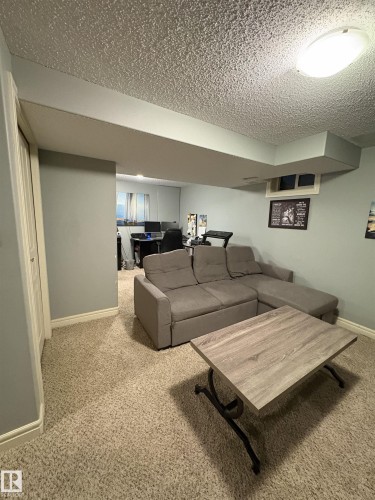 Carpeted recreation area featuring light gray wall paint, white baseboards, and a built-in closet with white bifold doors - 79 Akinsdale Gardens, St. Albert, AB - Indoor