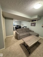 Carpeted recreation area featuring light gray wall paint, white baseboards, and a built-in closet with white bifold doors - 