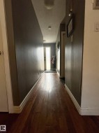 Wood-finish flooring throughout a hallway with painted walls - 