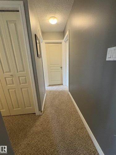 Carpeted hallway featuring a ceiling-mounted light fixture, painted walls, and white trim - 79 Akinsdale Gardens, St. Albert, AB - Indoor Photo Showing Other Room