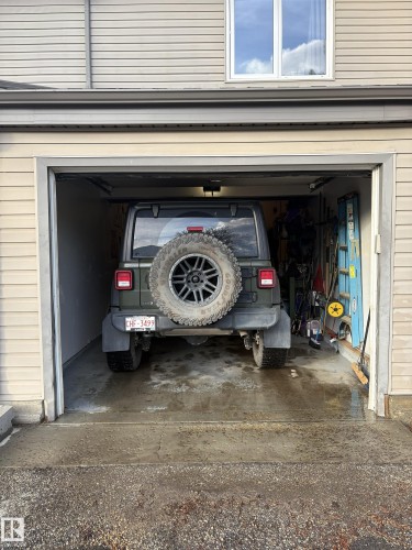 Attached single-car garage featuring a concrete floor and beige vinyl siding exterior - 79 Akinsdale Gardens, St. Albert, AB - Outdoor With Exterior