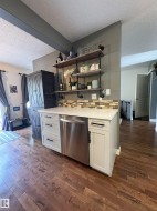 Wet bar area featuring white cabinetry, a stainless steel dishwasher, and a light-toned countertop - 