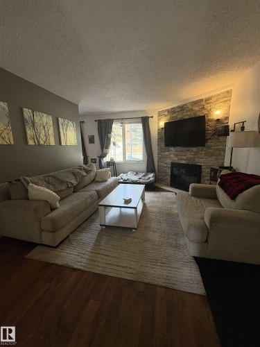 Living area with wood-finish flooring and a central area rug - 79 Akinsdale Gardens, St. Albert, AB - Indoor Photo Showing Living Room With Fireplace