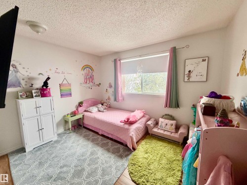 Wood-finish flooring with a white textured ceiling and a window featuring roller shades and decorative drapes - 3520 17B Avenue, Edmonton, AB - Indoor Photo Showing Bedroom