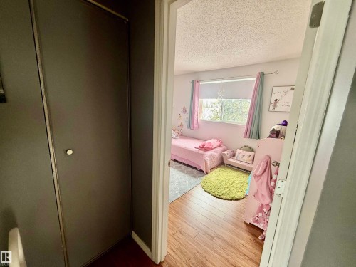 Room interior featuring wood-finish flooring, a window with roller shade, and a textured ceiling - 3520 17B Avenue, Edmonton, AB - Indoor Photo Showing Other Room
