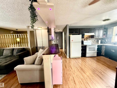 Kitchen featuring dark cabinetry, mosaic tile backsplash, and light wood-finish flooring - 3520 17B Avenue, Edmonton, AB - Indoor Photo Showing Other Room
