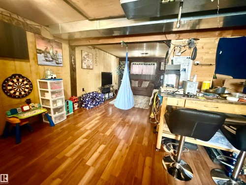 Spacious interior area featuring wood-finish flooring, exposed ceiling beams, and wood-paneled walls - 3520 17B Avenue, Edmonton, AB - Indoor