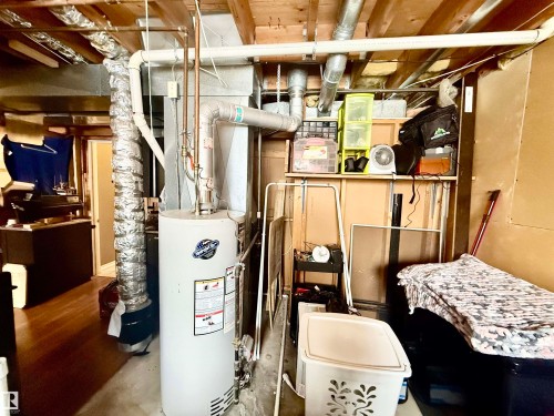 Utility space featuring exposed ceiling joists and ductwork, a water heater, and a concrete floor - 3520 17B Avenue, Edmonton, AB - Indoor Photo Showing Basement