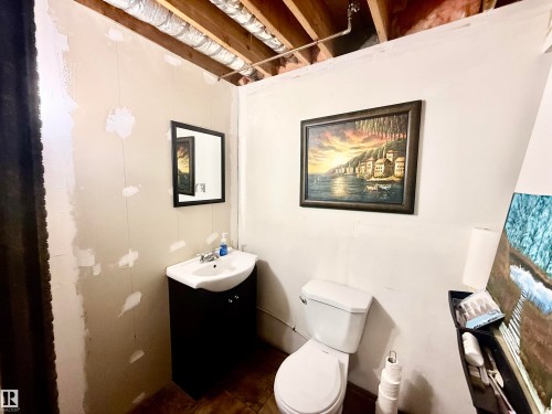 Compact bathroom featuring a white ceramic toilet and a dark wood-finish vanity with an integrated white sink - 3520 17B Avenue, Edmonton, AB - Indoor Photo Showing Bathroom