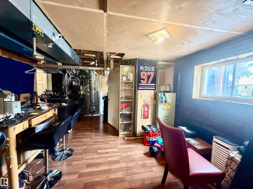 Finished basement area featuring wood-finish flooring, exposed ceiling joists, and a window providing natural light - 3520 17B Avenue, Edmonton, AB - Indoor Photo Showing Other Room