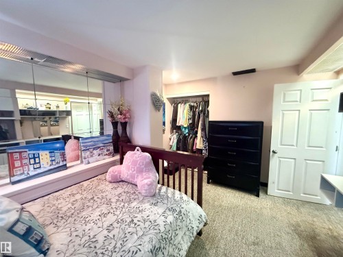 Bedroom featuring wall-to-wall carpeting, mirrored wall panels, a built-in open closet, and a white six-panel door - 3520 17B Avenue, Edmonton, AB - Indoor Photo Showing Bedroom