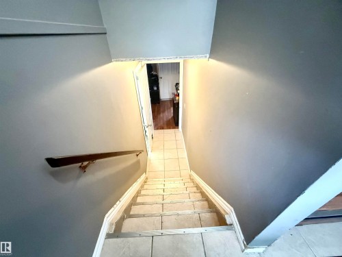 Staircase featuring tile treads, a dark wood-finish handrail, and grey painted walls - 3520 17B Avenue, Edmonton, AB - Indoor Photo Showing Other Room
