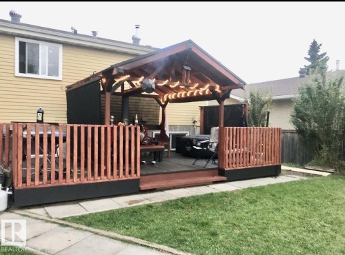 Expansive outdoor deck featuring a covered pergola, wood railings, and dark composite decking - 3520 17B Avenue, Edmonton, AB - Outdoor With Deck Patio Veranda With Exterior