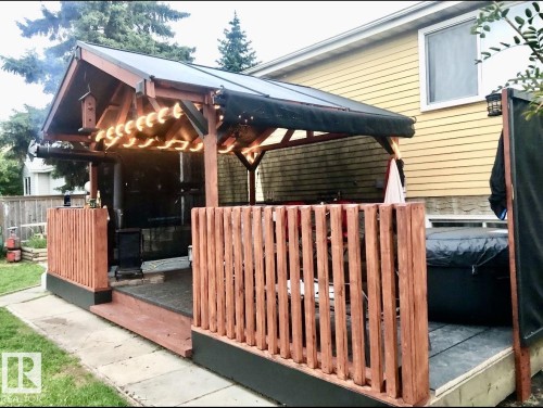 Expansive outdoor patio featuring a covered pergola, string lighting, wood railing, and a raised platform - 3520 17B Avenue, Edmonton, AB - Outdoor With Exterior