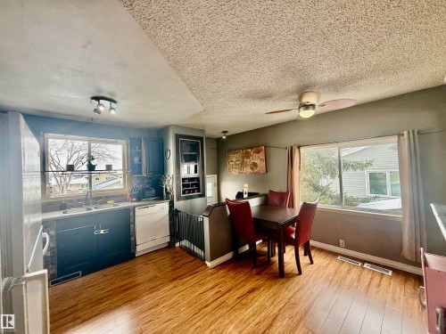 Open-concept kitchen and dining area featuring wood-finish flooring, dark cabinetry, and a tile backsplash - 3520 17B Avenue, Edmonton, AB - Indoor Photo Showing Dining Room