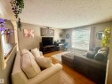 Living area featuring wood-finish flooring, a large window with blinds, and a built-in half wall with a wood-finish countertop - 3520 17B Avenue, Edmonton, AB  - Indoor Photo Showing Living Room 
