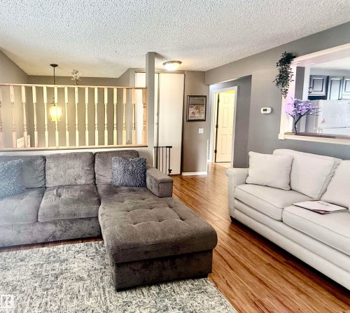 Open-concept living area with wood-finish flooring, a neutral color palette, and a built-in architectural half-wall with balusters - 3520 17B Avenue, Edmonton, AB - Indoor Photo Showing Living Room