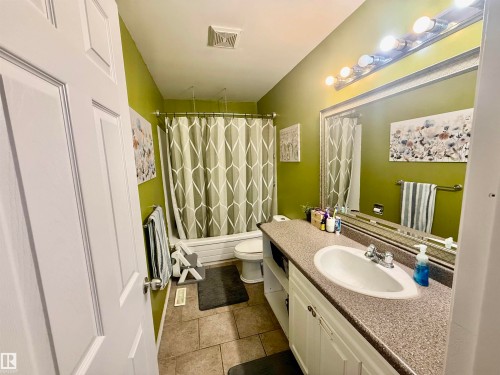 Full bathroom featuring a single vanity with an integrated sink, a speckled countertop, and white cabinetry - 3520 17B Avenue, Edmonton, AB - Indoor Photo Showing Bathroom