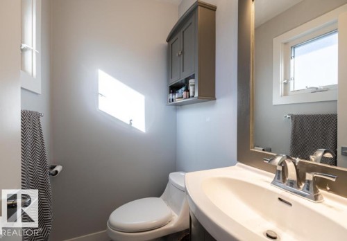 This bathroom features a contemporary vanity with a white sink, a wall-mounted mirror, and a window providing natural light in main bedroom. - 71 Labelle Crescent, St. Albert, AB - Indoor Photo Showing Bathroom