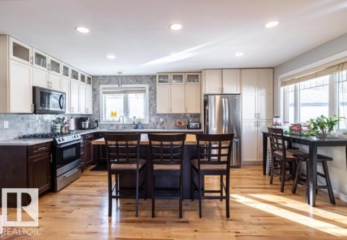 The kitchen features hardwood floors, a central island with seating, stainless steel appliances, and ample cabinetry - 71 Labelle Crescent, St. Albert, AB - Indoor