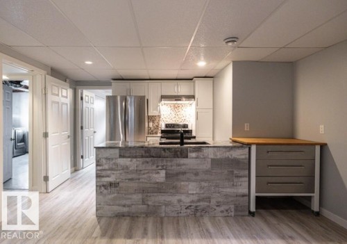 The kitchen features a contemporary island with a sink, white cabinetry, and stainless steel appliances in basement. - 71 Labelle Crescent, St. Albert, AB - Indoor