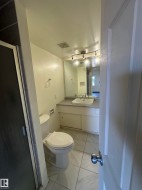Bathroom featuring a white toilet, vanity with undermount sink, and track lighting - 