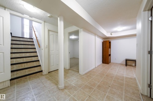 This versatile area features light-colored tile flooring, a staircase with dark treads, and a white ceiling with recessed lighting - 3518 78 Street, Edmonton, AB - Indoor Photo Showing Other Room