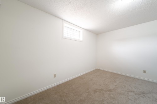 The room features a neutral color palette, carpeted flooring, and a window providing natural light - 3518 78 Street, Edmonton, AB - Indoor Photo Showing Other Room