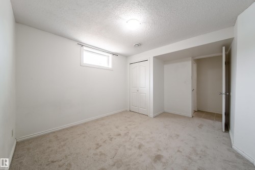 This room features light-colored carpet flooring, a window, and a closet with bifold doors - 3518 78 Street, Edmonton, AB - Indoor Photo Showing Other Room