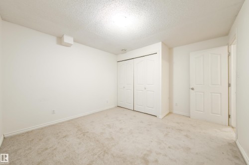 This room features light-colored carpeting and white walls, creating a bright and neutral interior - 3518 78 Street, Edmonton, AB - Indoor Photo Showing Other Room
