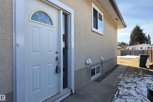 The property features a white panel door with an arched window, a side window, and textured exterior siding - 3518 78 Street, Edmonton, AB - Outdoor With Exterior