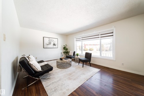 Spacious living area featuring rich hardwood floors, a large window providing natural light, and neutral wall tones - 3518 78 Street, Edmonton, AB - Indoor