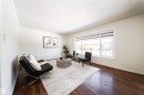 Spacious living area featuring rich hardwood floors, a large window providing natural light, and neutral wall tones - 3518 78 Street, Edmonton, AB  - Indoor 