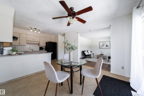 This property features a kitchen with light-colored cabinetry, a tile backsplash, and a black refrigerator - 3518 78 Street, Edmonton, AB - Indoor