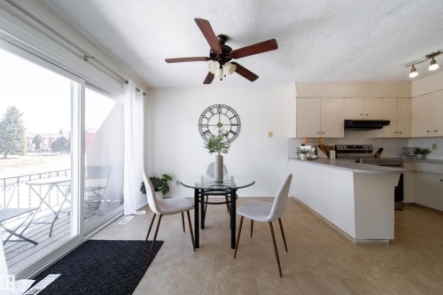 This inviting space features a kitchen with light-colored cabinetry, a breakfast bar, and an electric range with an overhead exhaust fan - 3518 78 Street, Edmonton, AB - Indoor