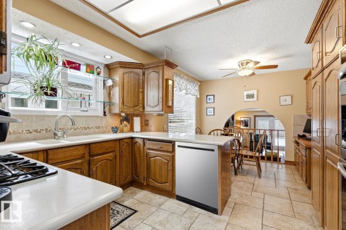 Kitchen with wood-finish cabinetry, light-toned countertops, and a tile backsplash - 11707 29 Avenue Nw, Edmonton, AB - Indoor Photo Showing Kitchen With Double Sink