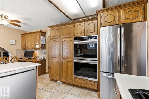 Kitchen featuring wood cabinetry, stainless steel appliances, and tile flooring - 11707 29 Avenue Nw, Edmonton, AB - Indoor Photo Showing Kitchen