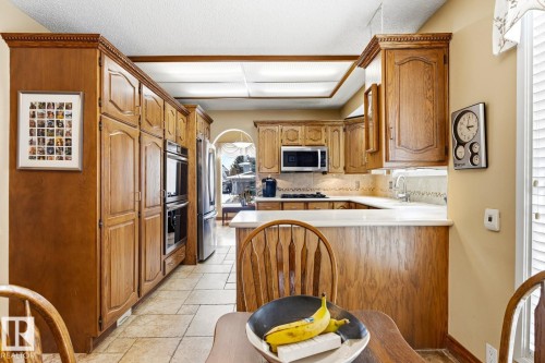 Kitchen featuring extensive wood cabinetry, integrated double ovens, stainless steel refrigerator, and a built-in microwave - 11707 29 Avenue Nw, Edmonton, AB - Indoor Photo Showing Kitchen