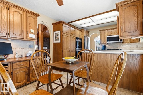 Kitchen featuring extensive wood cabinetry, tile flooring, recessed lighting, and a built-in microwave - 11707 29 Avenue Nw, Edmonton, AB - Indoor